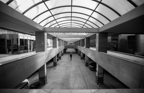Free A man walking under a glass ceiling in a modern parking structure in Ankara, Türkiye. Stock Photo