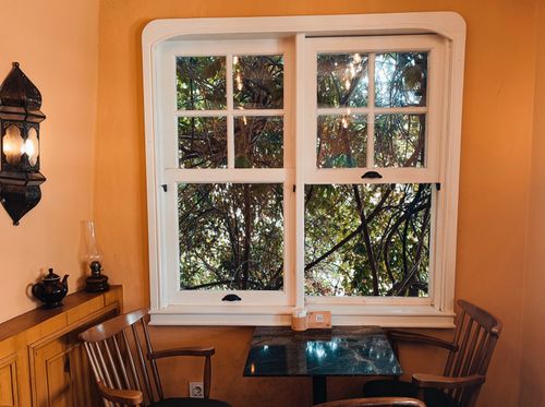 Free Warm and nostalgic interior with chairs and a window view of lush greenery. Stock Photo