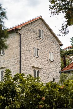 Charming stone house in Montenegro with traditional shuttered windows and red-tiled roof.
