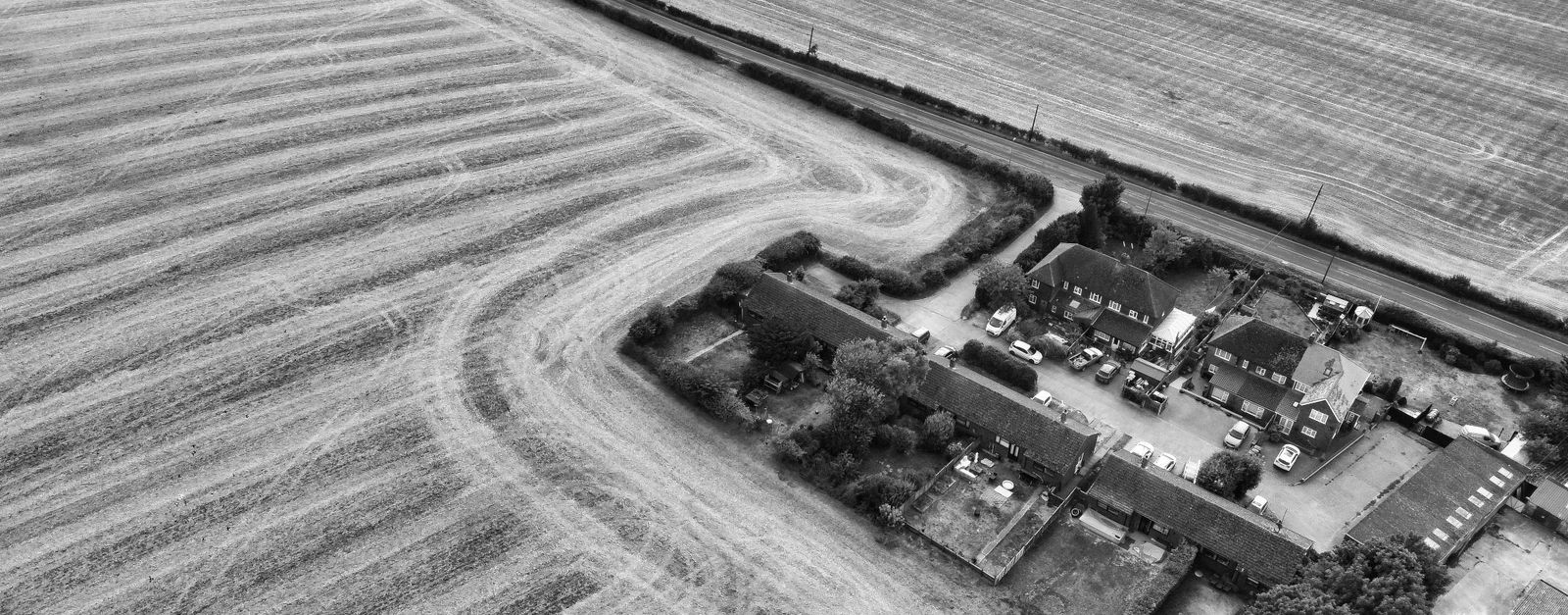 Black and white aerial shot of fields and farmhouses in Eaton Bray, England.
