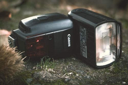 Free Two camera flashes positioned on mossy ground, highlighting outdoor photography gear. Stock Photo