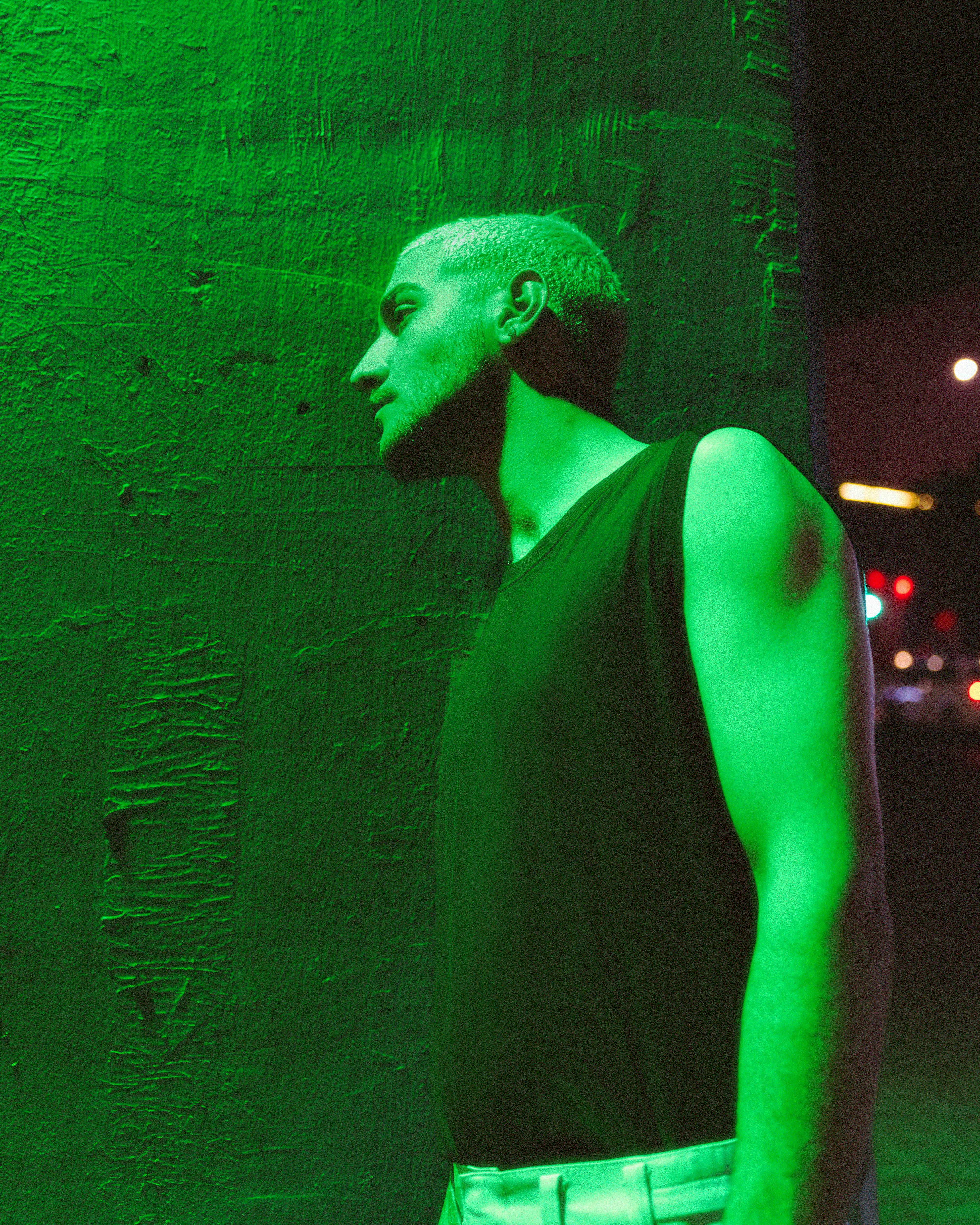 Striking portrait of a man with green lighting creating an urban, edgy mood.