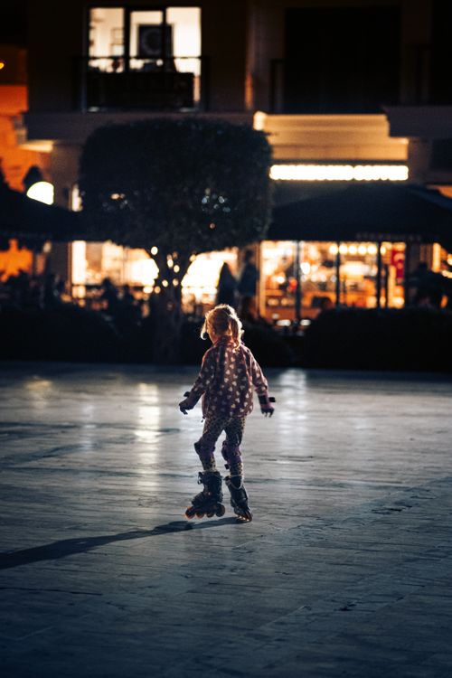 Free A child roller skates joyfully at night in an urban setting, radiating fun and activity. Stock Photo