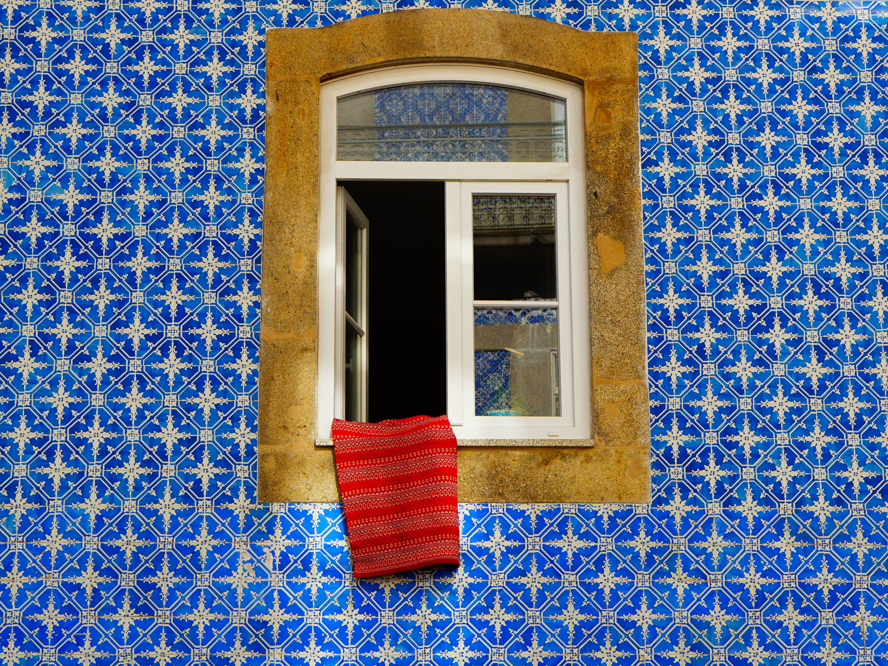 A classic Portuguese window framed by vibrant azulejo tiles in blue and white