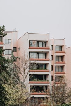Five-story residential building with red balconies and white walls.