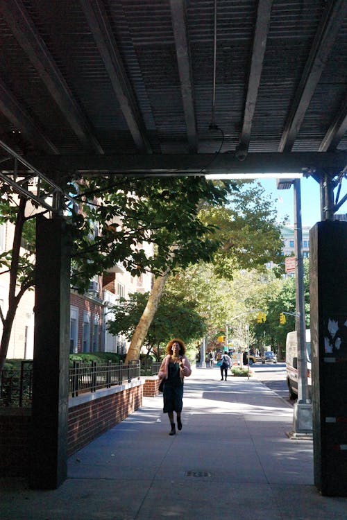 Candid Photo of a Woman Walking on a Sidewalk in City in Summer 