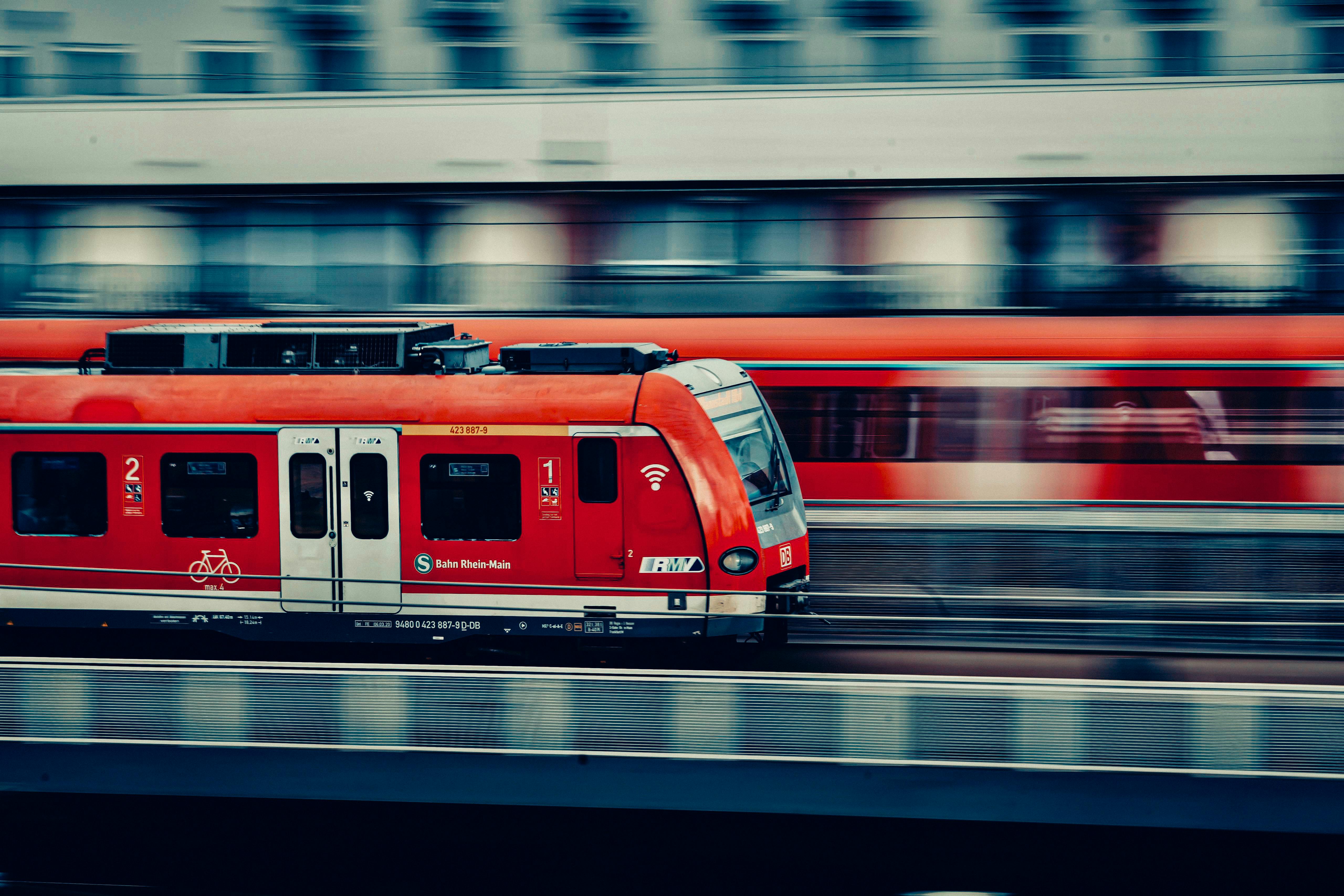 Captivating image of a red passenger train speeding through a cityscape, showcasing dynamic motion.