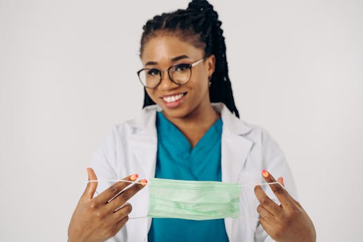 Confident female doctor in glasses holding a surgical mask, promoting healthcare.