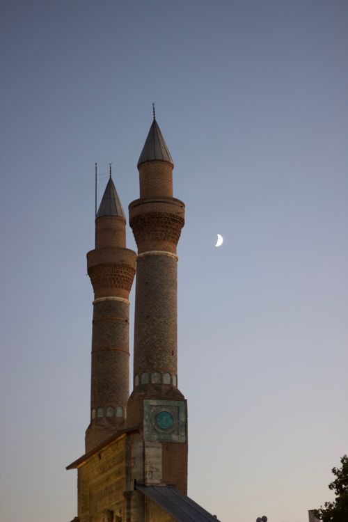 Free Silhouette of the Twin Minarets of Cifte Minareli Medrese against a crescent moon in Sivas, Türkiye. Stock Photo