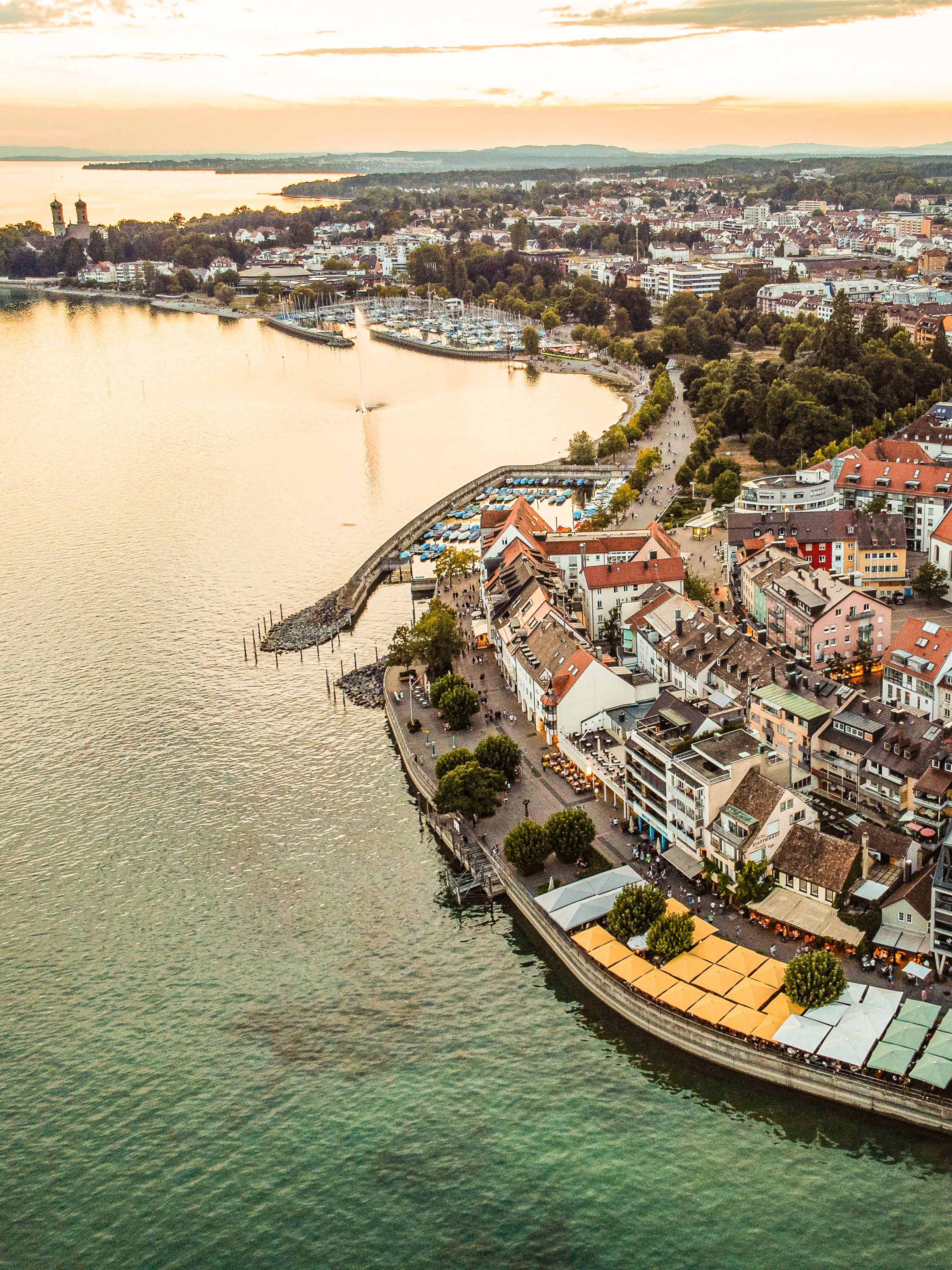 Aerial shot of Friedrichshafen harbor, showcasing the scenic cityscape and waterfront at sunset.