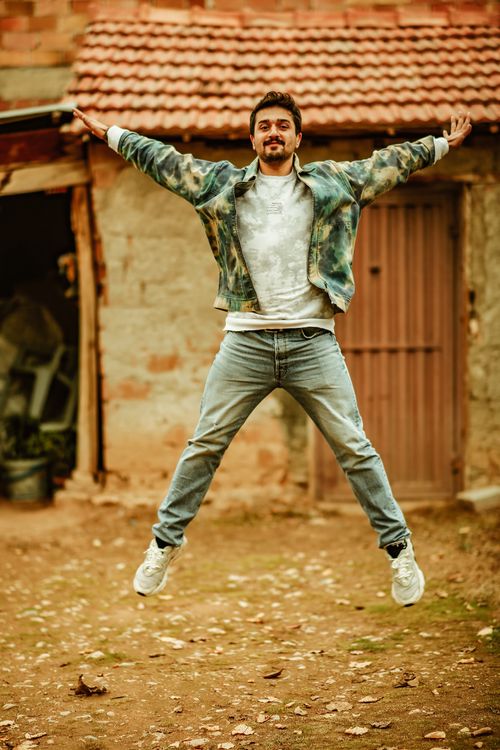 Free Portrait of a young man energetically jumping rural outdoors in denim clothes. Stock Photo