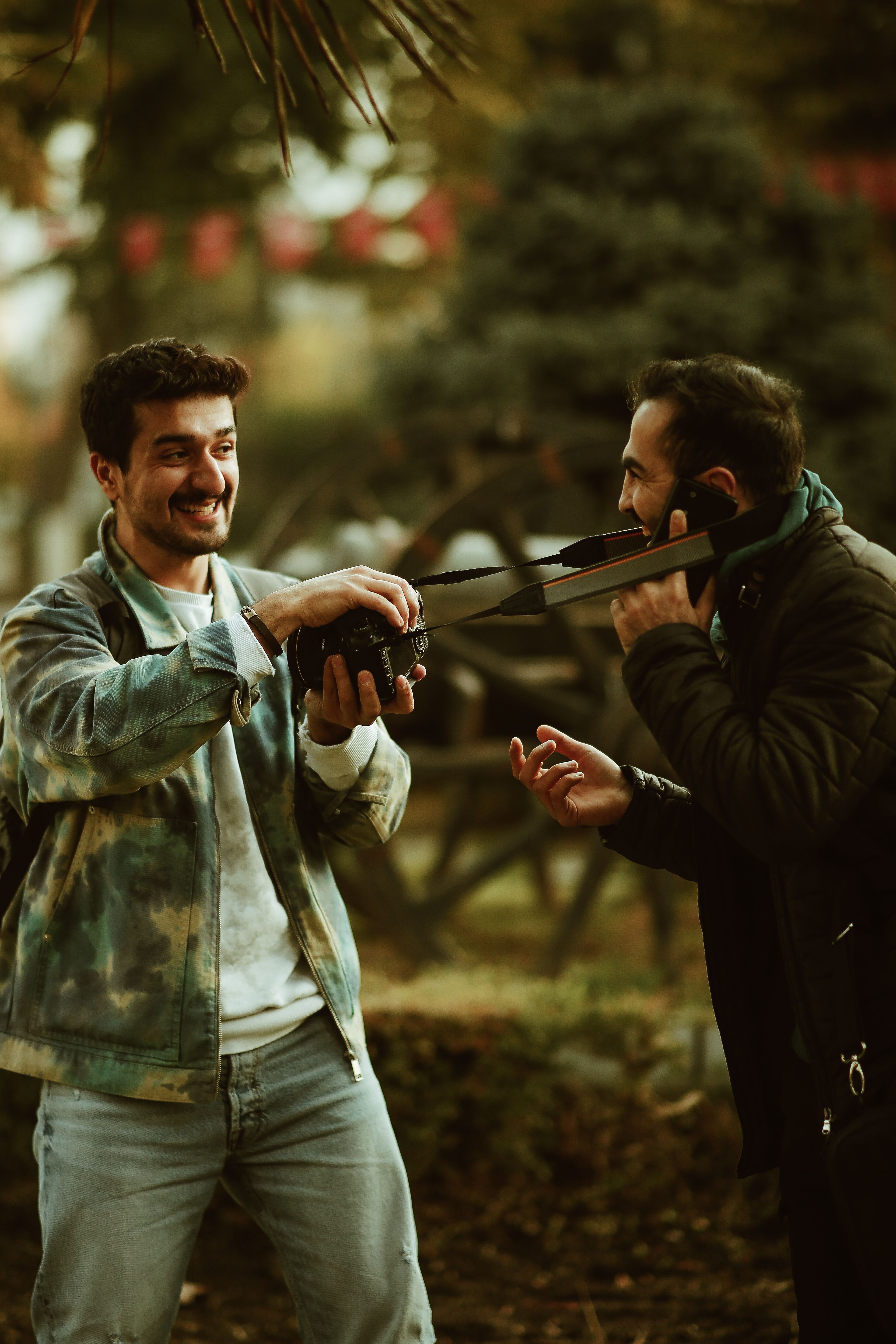 Two friends sharing a joyful moment with a camera in a scenic park setting.