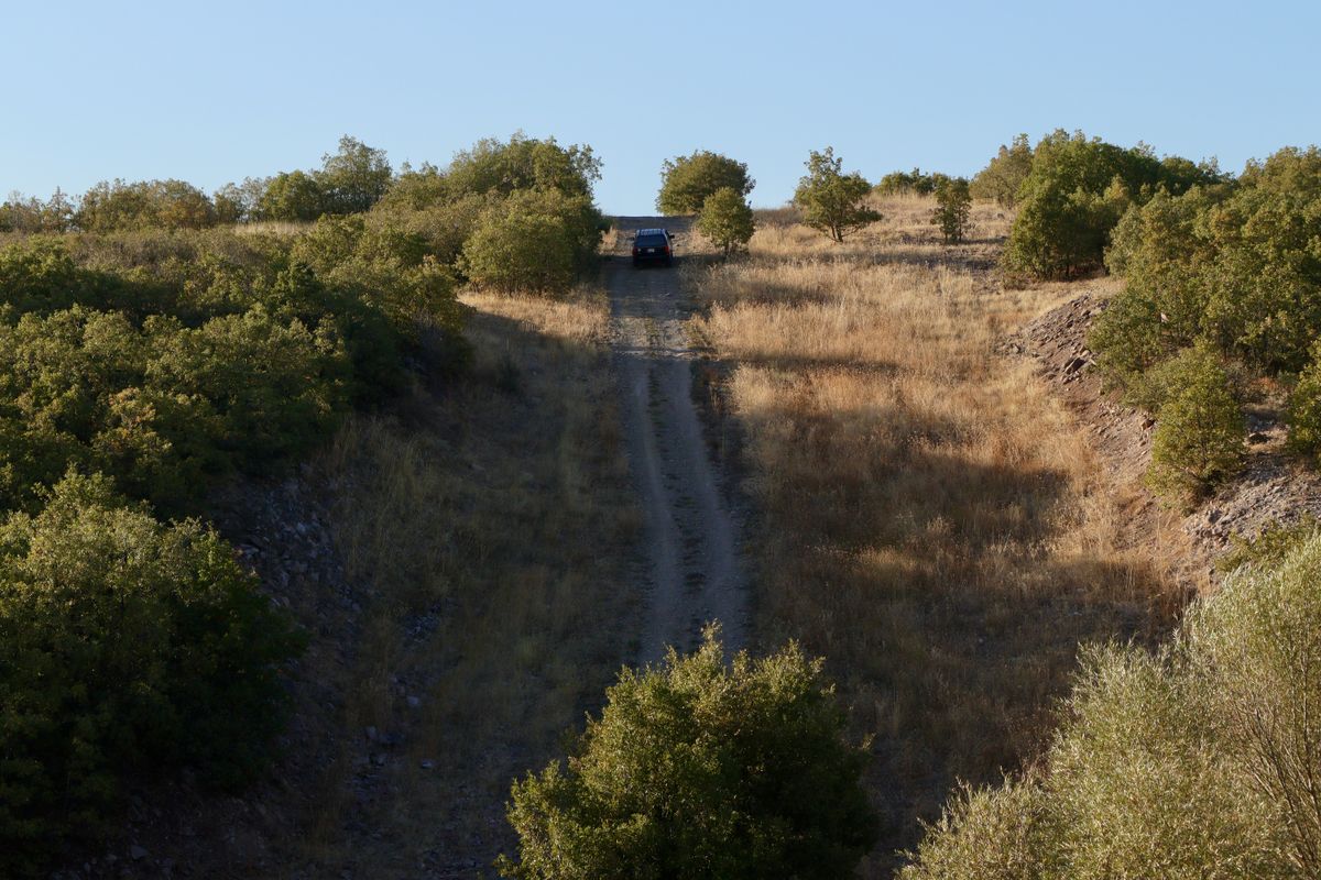 SUV climbing a rough two-track gravel road on a dry hillside in the backcountry