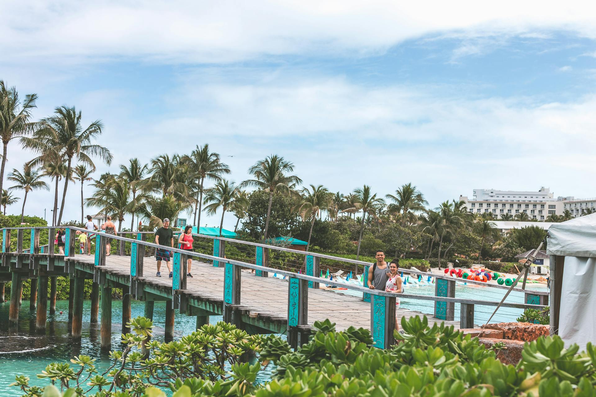 Couples and families enjoying a summer day on a tropical resort bridge by the ocean.