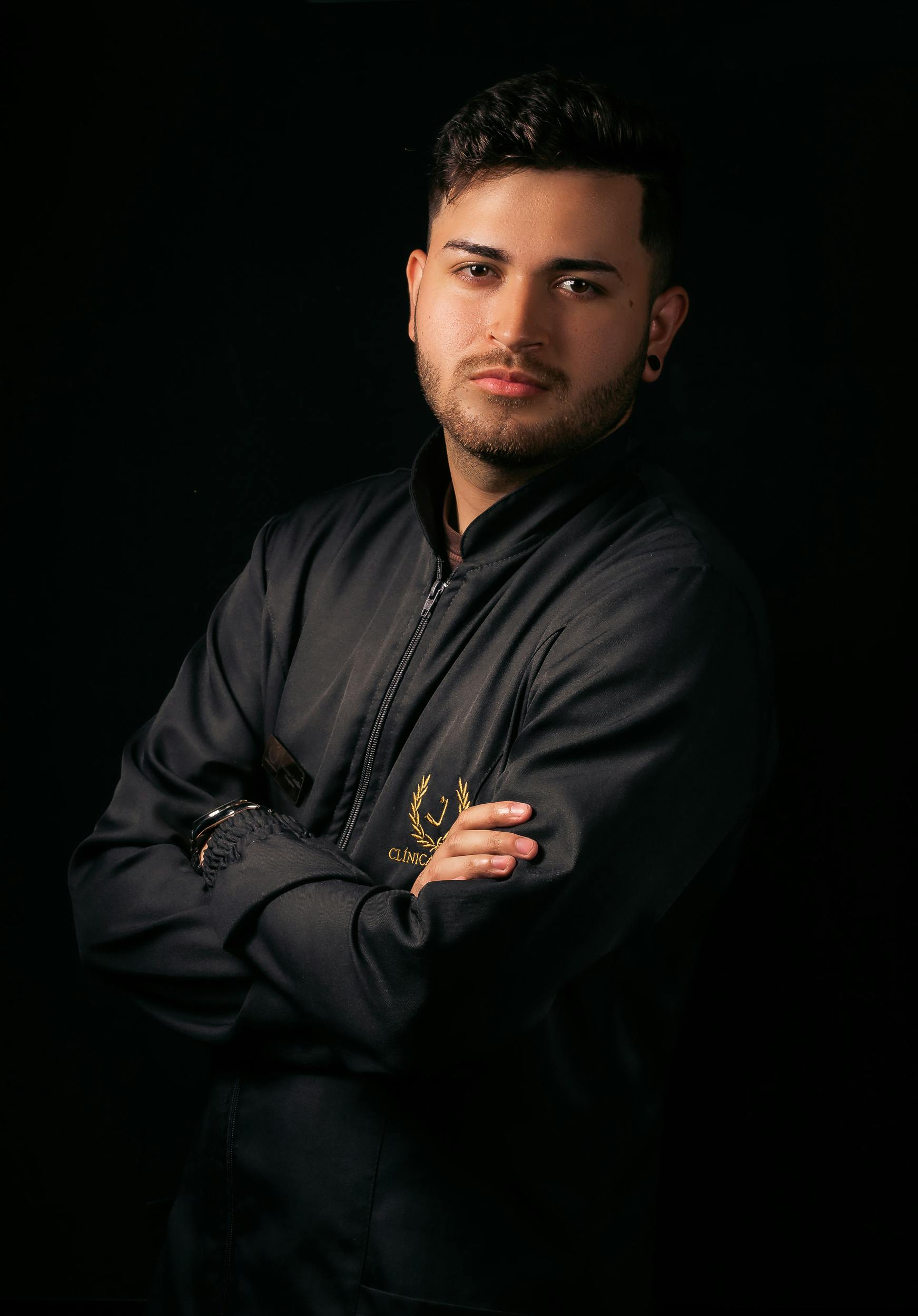 Confident man posing in a black jacket against a dark background