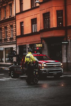 Urban setting with police patrol on Segway and a tow truck parked on a wet city street.