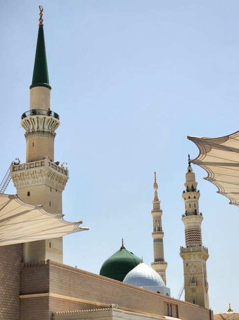 Iconic minarets and dome of Al-Masjid an-Nabawi in Medina under clear sky.