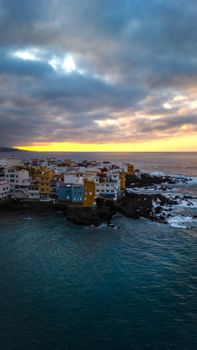 A stunning aerial view of the colorful buildings along the Puerto de la Cruz coastline at sunset in Tenerife, Spain.
