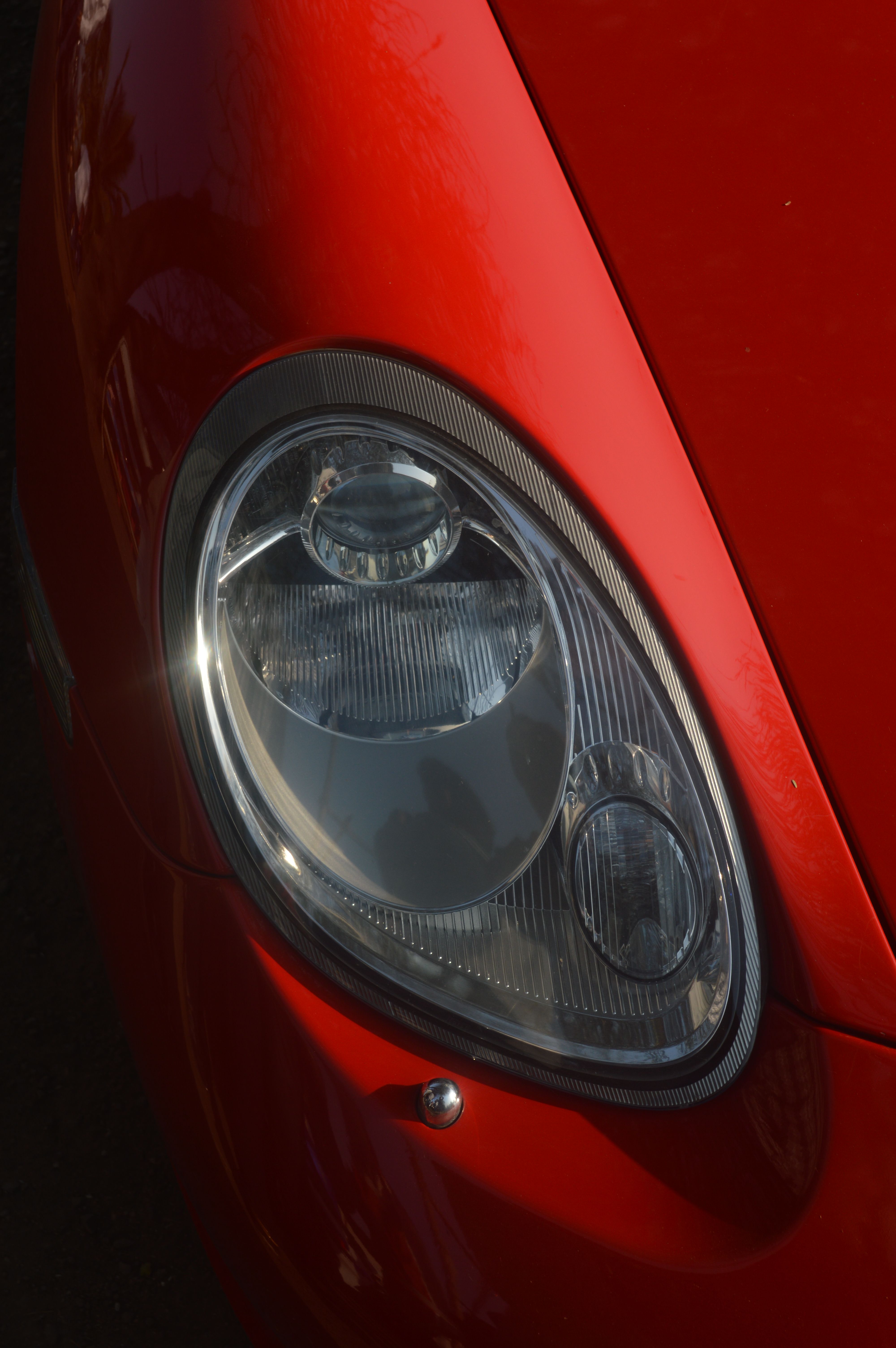 Detailed close-up of a red sports car headlight showcasing design.