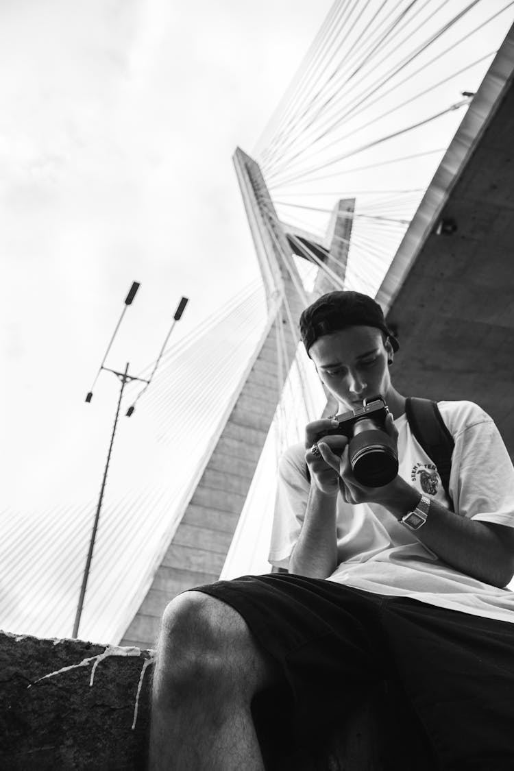 Man Looking At His Camera Under The Bridge