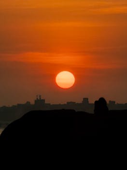 Silhouette against a vibrant sunset over Passagem RJ, capturing the serene skyline.