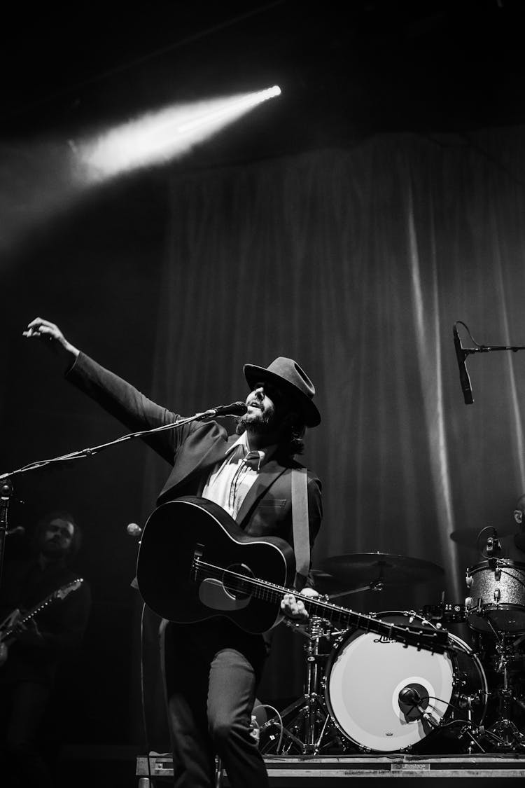 Grayscale Photography Of Man With Guitar Performing On Stage