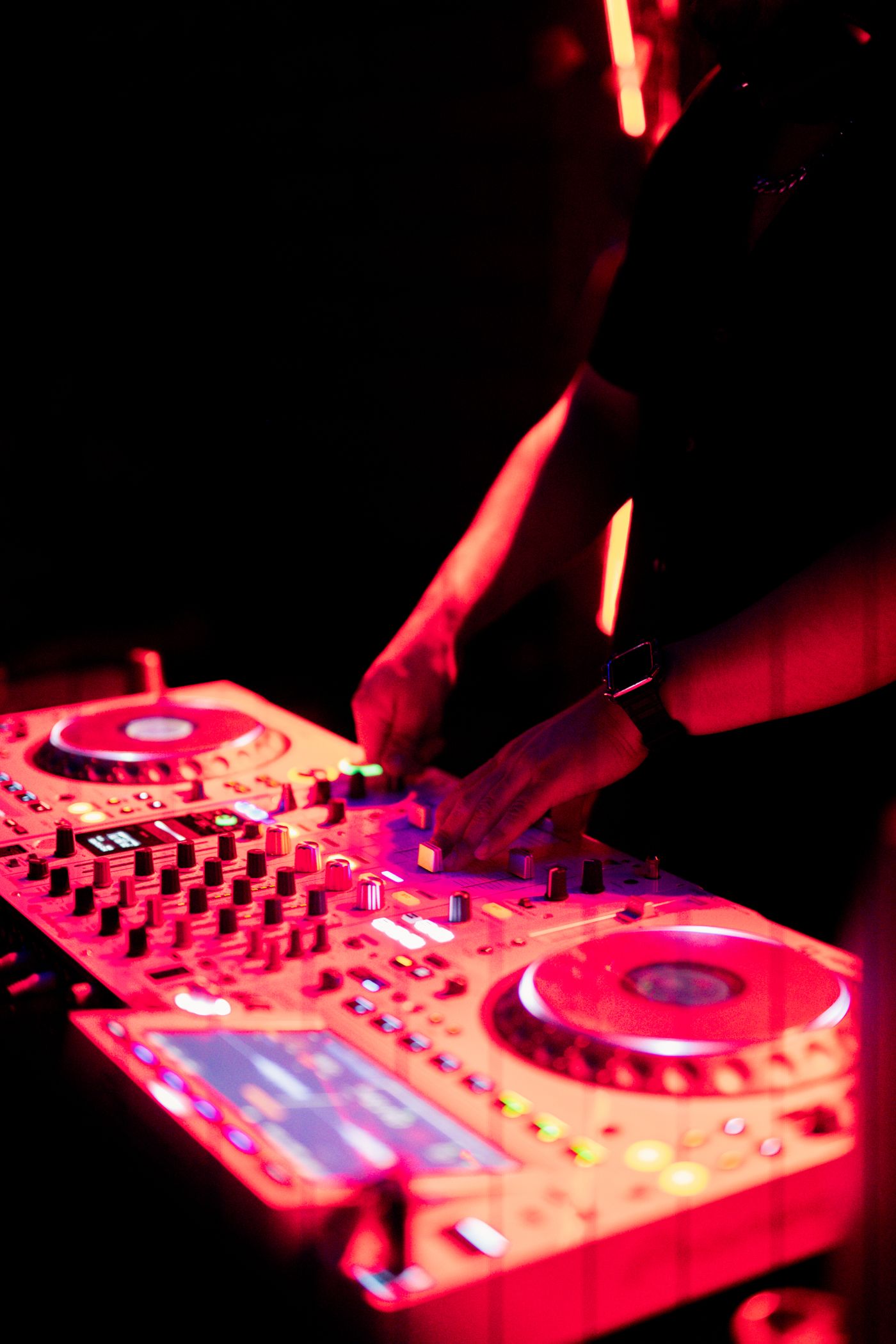 DJ pinchando en cabina de club con luces de neón violeta en Madrid
