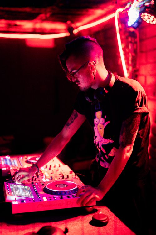 Free DJ playing music in a nightclub with vibrant red lighting, creating an energetic atmosphere. Stock Photo
