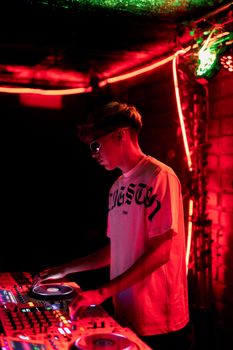 DJ mixing music at a nightclub with vibrant neon lighting, creating an energetic atmosphere.