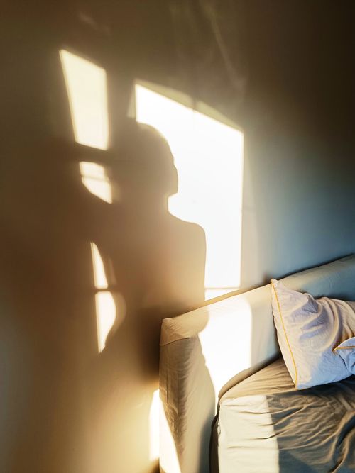 Free Shadow of a person on the wall with sunlight streaming into a cozy bedroom. Stock Photo