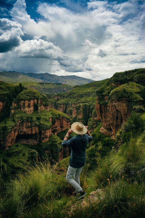 Free Person with hat overlooking vibrant Cuzco canyon, capturing adventure and natural beauty. Stock Photo
