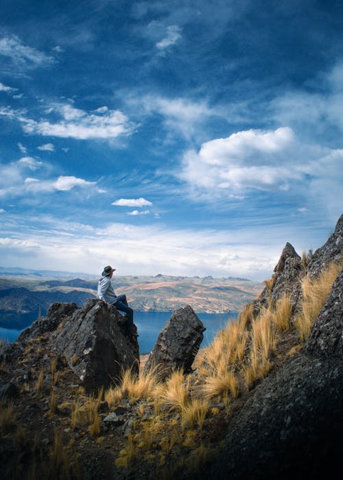 A Man Sitting on Top of a Rocky Mountain 