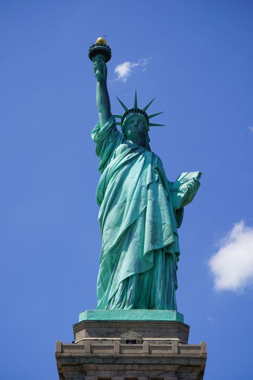 Free Majestic view of the Statue of Liberty with a vibrant blue sky backdrop. Icon of freedom in New York. Stock Photo