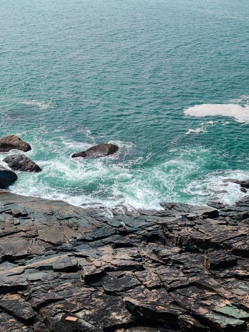 Free A breathtaking view of the rocky coast and turquoise sea in Shiroda, India. Stock Photo