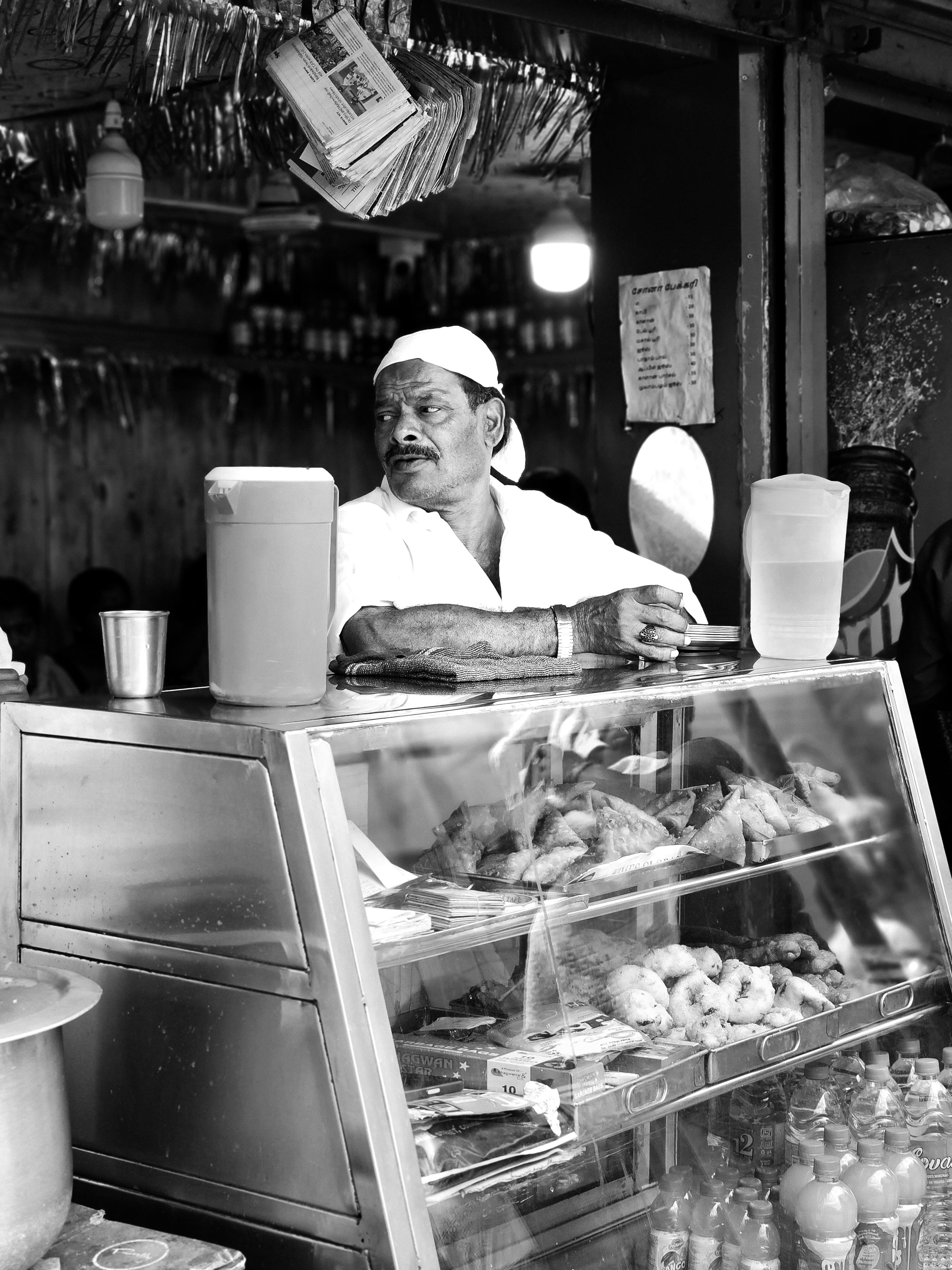 man selling food on a street market in black and white