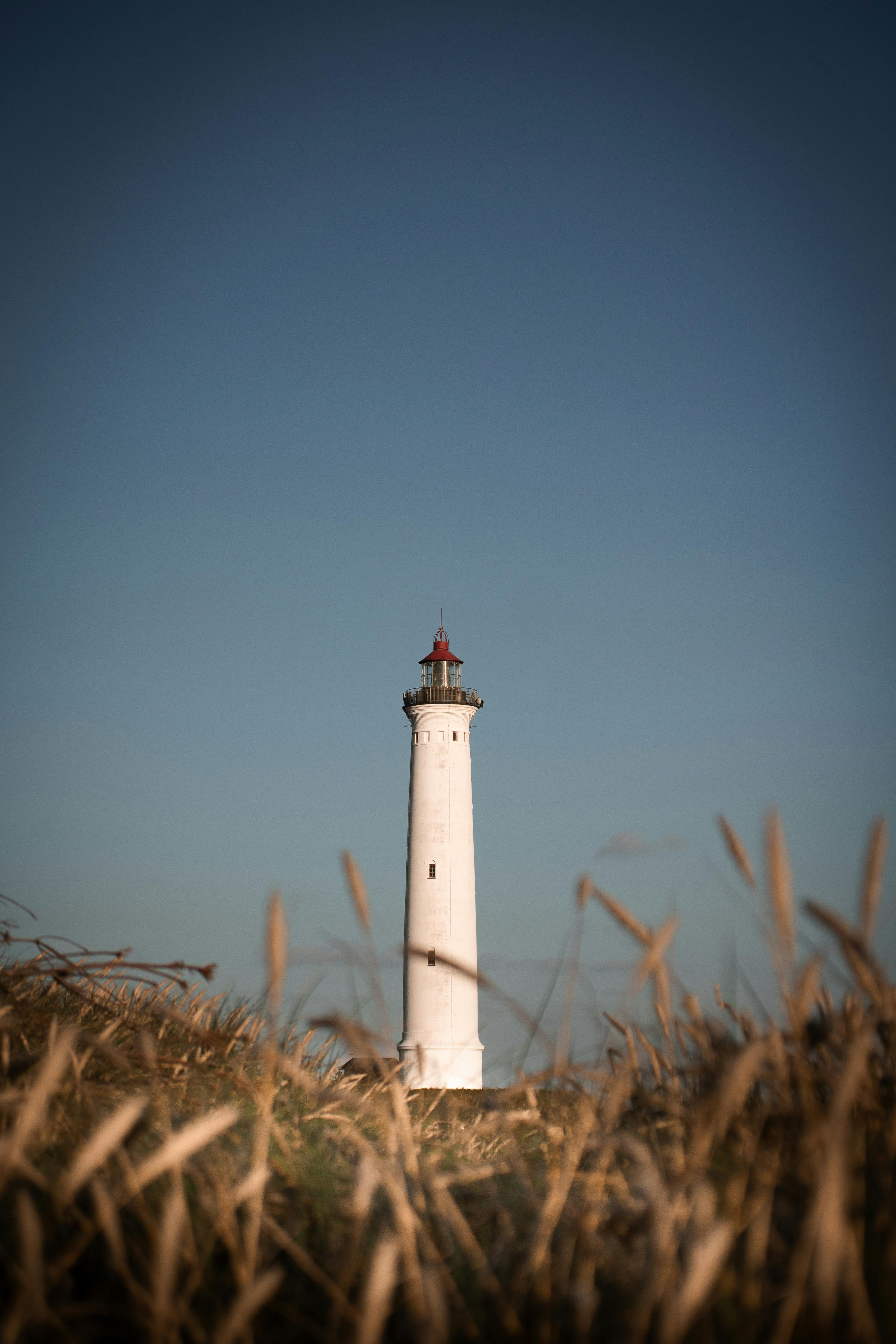 A striking lighthouse stands tall against a clear blue sky in Hvide Sande, Denmark.