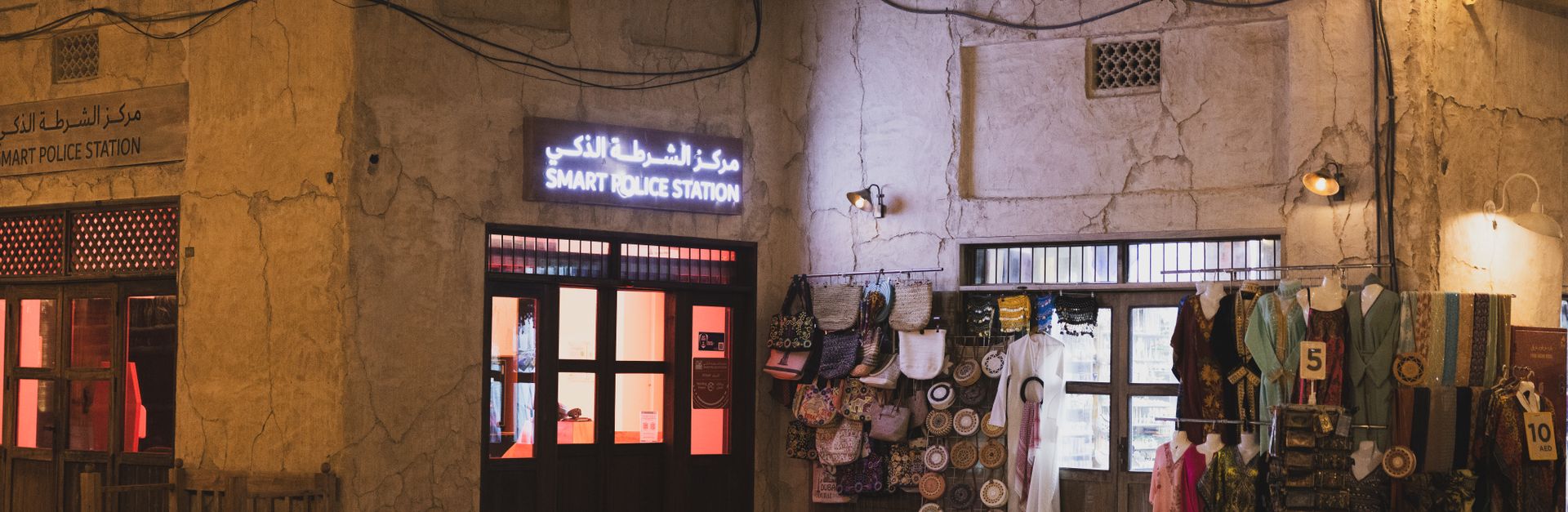 Illuminated Smart Police Station in Dubai's Al Seef district at night with traditional shops.