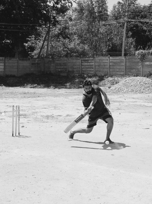 Free A man skillfully playing cricket outdoors, captured in striking black and white. Stock Photo