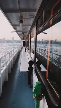 A ferry view of Istanbul's skyline over the sea at sunset, featuring calm waters and urban landscape.