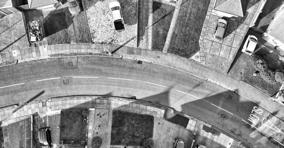 Black and white aerial view capturing a suburban neighborhood in Bedfordshire, England with parked cars and residential rooftops.