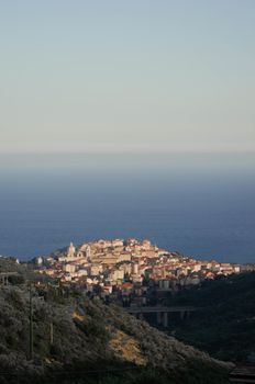 A scenic aerial view of a charming coastal town with hills and sea in the background.