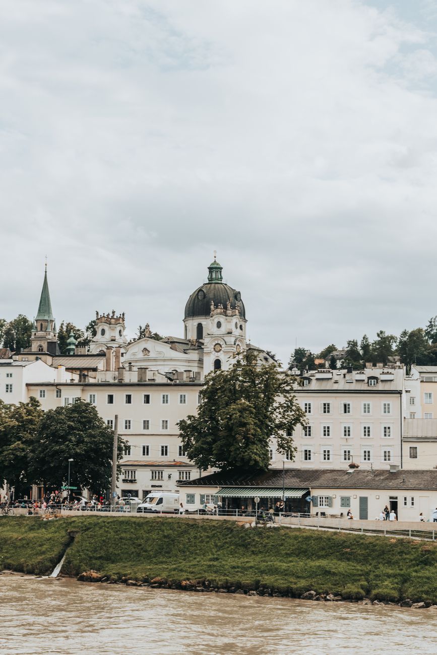 Scenisch uitzicht op de historische skyline van Salzburg en de Salzach rivier met pittoreske gebouwen en een koepel.