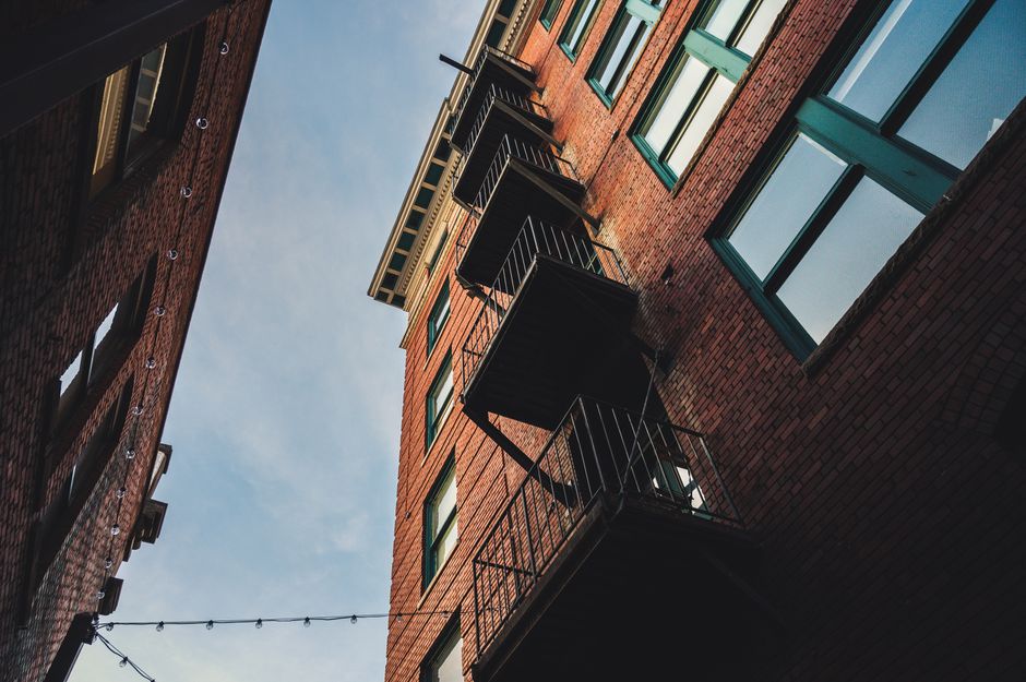 A striking low angle shot of red brick urban architecture and balconies under a clear sky.