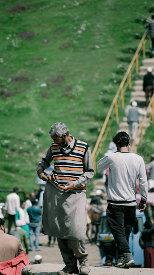Elderly Man Standing and People Walking behind