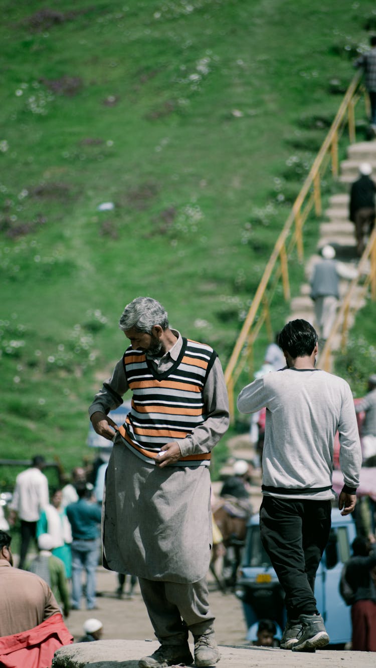 Elderly Man Standing And People Walking Behind