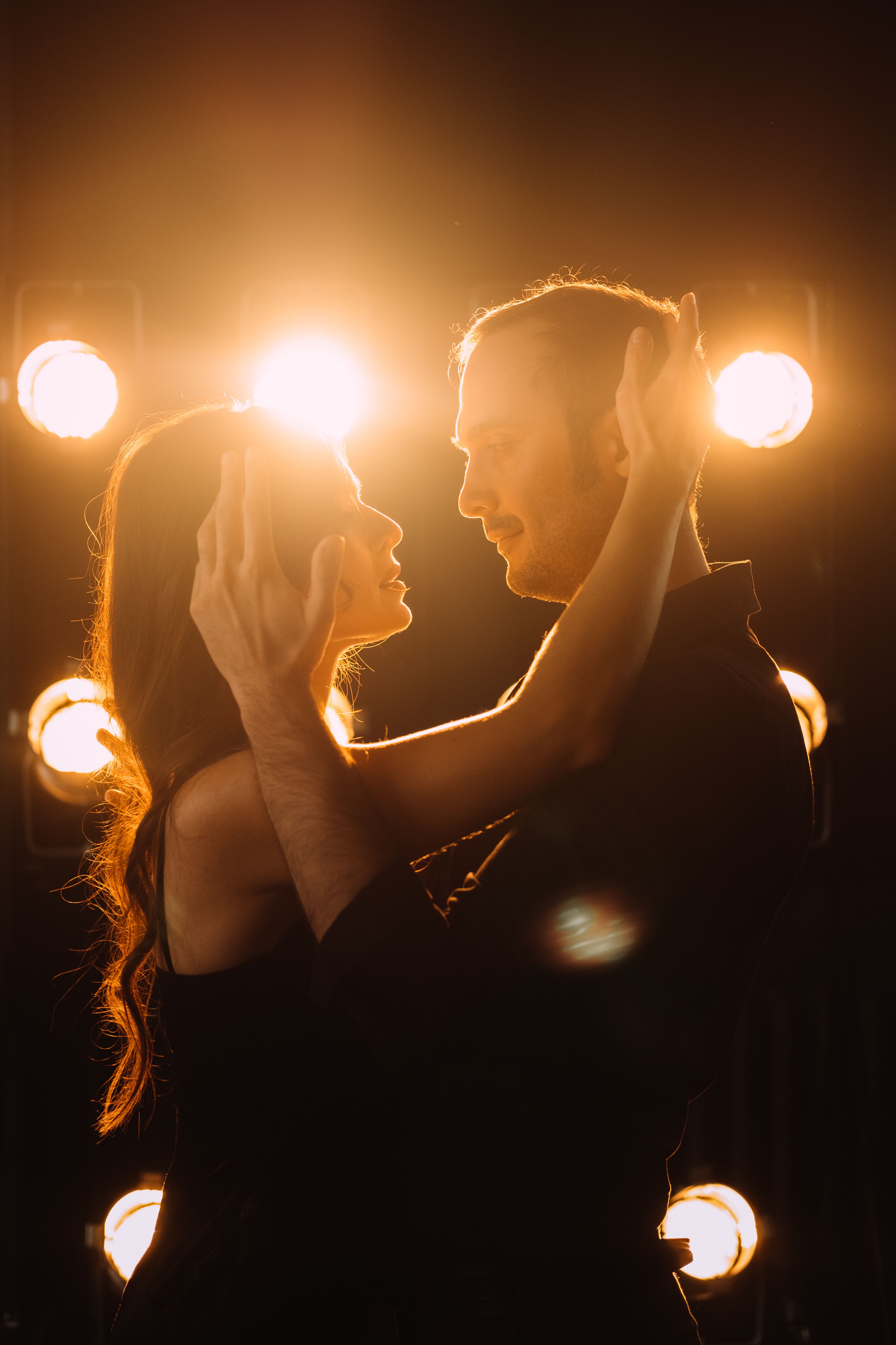Rumba — couple in a close, romantic embrace under warm stage lights. Stock photo.