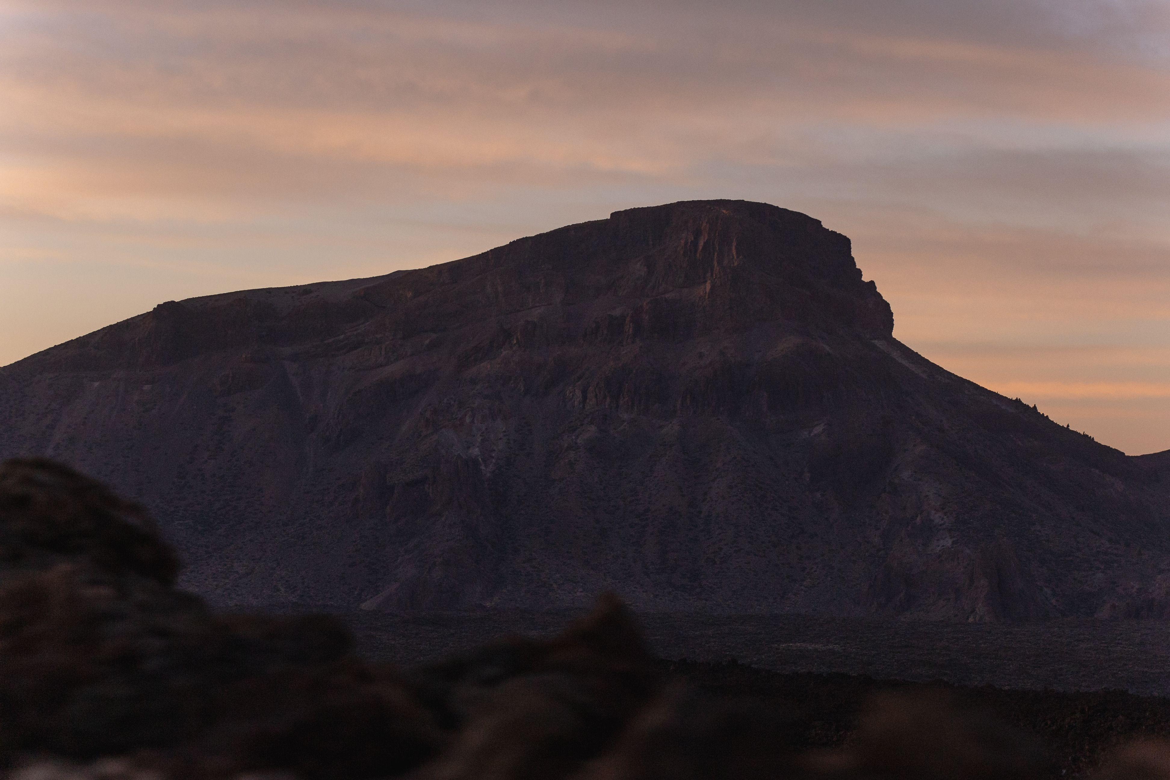 A stunning silhouette of a rugged mountain against a dusky cloudscape.