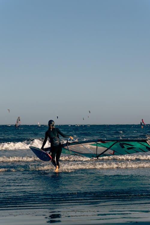 Woman Carrying a Wind Surfing Board to the Sea