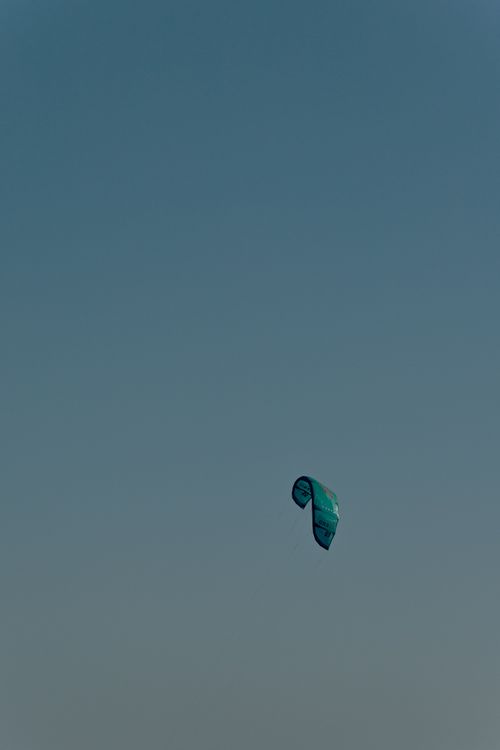 Free A lone kite surfing parachute floats in a clear blue sky, capturing adventure and freedom. Stock Photo