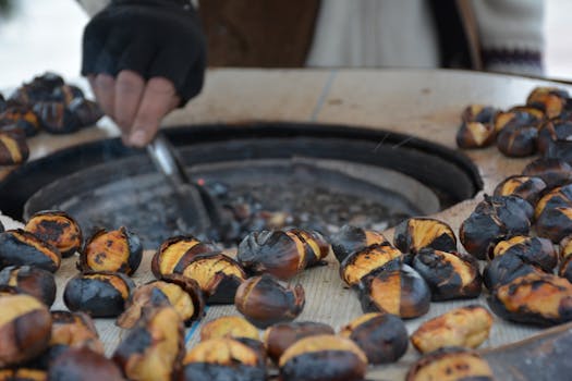 A street vendor roasts chestnuts over a hot grill, offering a warm snack.